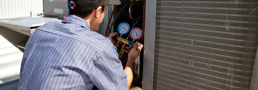 HVAC technician servicing a condenser unit in Darien